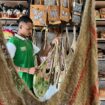 Tampak salah satu pegawai toko saat merapikan noken di salah satu tokoh di Jayapura, Sabtu (29/03/2025). Noken kini bisa dibeli di shopee tanpa haru terbang ke Papua / Erianto - Euforia.id