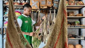Tampak salah satu pegawai toko saat merapikan noken di salah satu tokoh di Jayapura, Sabtu (29/03/2025). Noken kini bisa dibeli di shopee tanpa haru terbang ke Papua / Erianto - Euforia.id