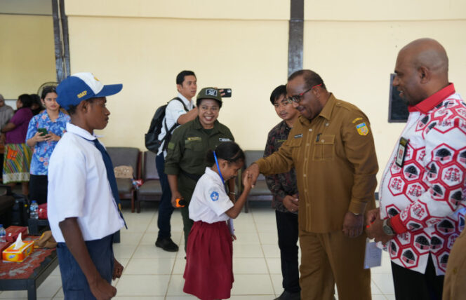 
					Seorang siswa bersalaman dengan Asisten 1 Setda Papua, Yohanes Walilo / Papua.go.id