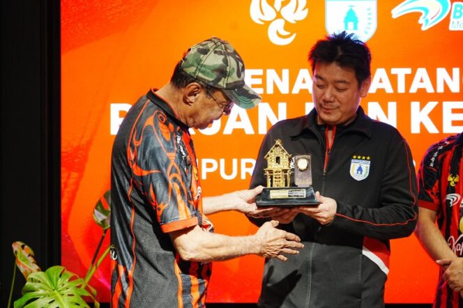 
					Manajer Persipura, Owen Rahadian menerima plakat dari Bank Papua