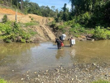Tampak personil Polres Keerom Briptu Muflihuddin dan Bripda Rian Merahabia ketika menyeberangi sungai ketika melakukan pengawalan logistik Pemilu 2024 menuju Kampung Milki, Distrik Towe, Keerom pada 15 Februari 2024 silam / Istimewa