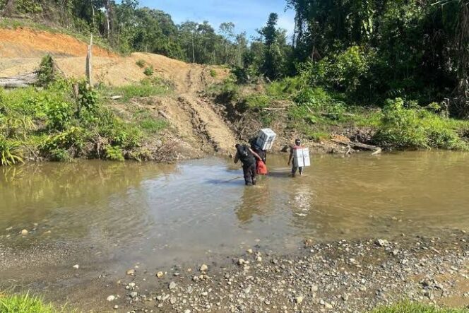 
					Tampak personil Polres Keerom Briptu Muflihuddin dan Bripda Rian Merahabia ketika menyeberangi sungai ketika melakukan pengawalan logistik Pemilu 2024 menuju Kampung Milki, Distrik Towe, Keerom pada 15 Februari 2024 silam / Istimewa